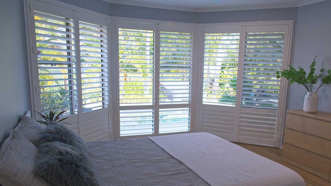 luxury white indoor plantation shutters in bedroom